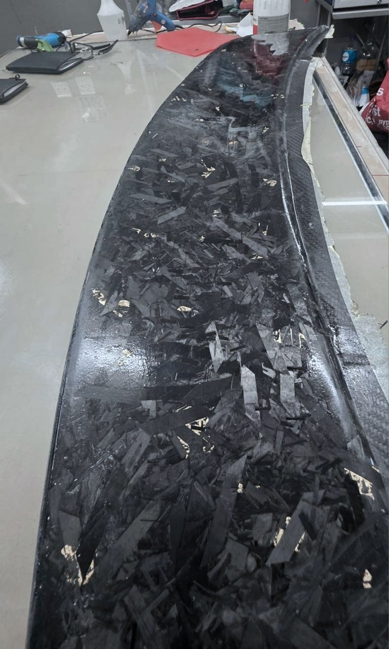 The cured carbon grille lifted out of the mould before trimming.